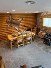 Misc room with a textured ceiling, rustic walls, and dark colored carpet