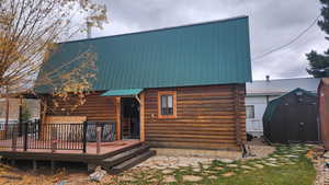 Back of house with a storage shed and a deck