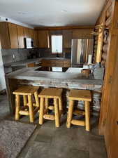 Kitchen featuring sink, decorative backsplash, appliances with stainless steel finishes, and kitchen peninsula