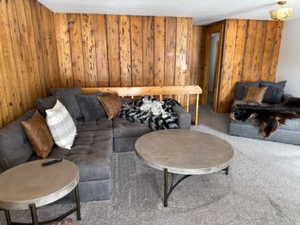 Carpeted living room featuring wooden walls