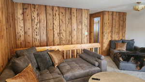 Living room featuring carpet flooring, a textured ceiling, and wooden walls