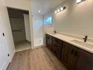 Bathroom featuring hardwood / wood-style flooring, vanity, and walk in shower