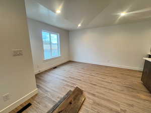 Empty room with light hardwood / wood-style flooring and lofted ceiling