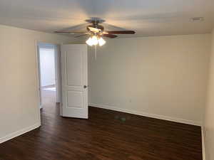 Empty room featuring a textured ceiling, ceiling fan, and dark hardwood / wood-style flooring