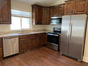 Kitchen with sink, dark wood-type flooring, appliances with stainless steel finishes, and light stone counters