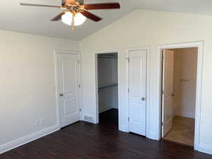 Unfurnished bedroom with a walk in closet, ceiling fan, vaulted ceiling, and dark hardwood / wood-style flooring