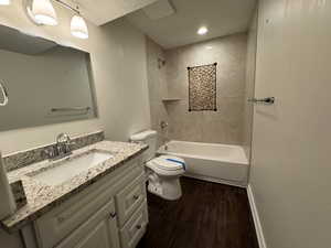 Full bathroom with a textured ceiling, toilet, vanity, hardwood / wood-style flooring, and tiled shower / bath combo