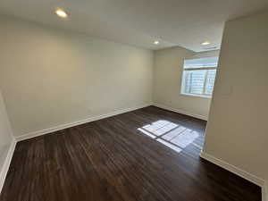 Spare room with dark wood-type flooring and a textured ceiling