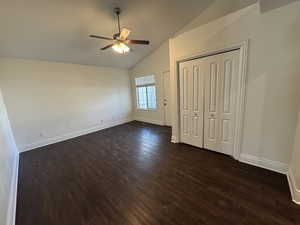 Unfurnished bedroom featuring vaulted ceiling, ceiling fan, a closet, and dark hardwood / wood-style flooring