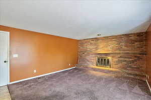 Unfurnished living room featuring a textured ceiling, a fireplace, and carpet floors