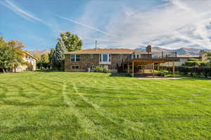 Rear view of property featuring a deck with mountain view, a patio area, and a yard