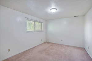 Carpeted empty room featuring a textured ceiling