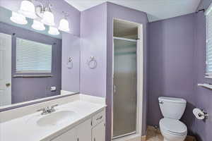 Bathroom featuring toilet, walk in shower, vanity, and tile patterned floors