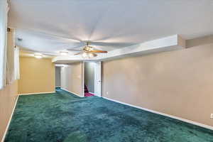 Basement featuring ceiling fan, a textured ceiling, and dark carpet