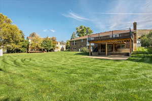 View of yard featuring a wooden deck and a patio