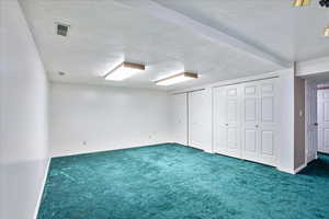 Basement with dark colored carpet and a textured ceiling