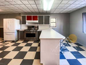 Kitchen featuring plenty of natural light, kitchen peninsula, white refrigerator, and electric stove