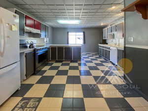 Kitchen featuring plenty of natural light, kitchen peninsula, white refrigerator, and electric stove