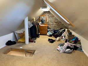 Bonus room featuring carpet, lofted ceiling, and brick wall