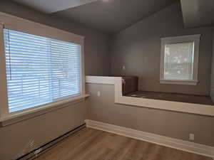 Empty room with wood-type flooring and lofted ceiling