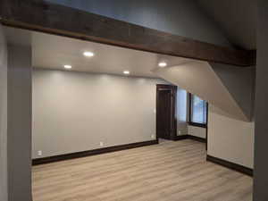 Bonus room with vaulted ceiling with beams and light wood-type flooring