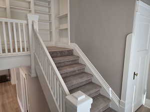 Staircase featuring hardwood / wood-style floors and built in features