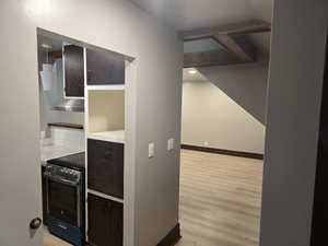 Kitchen featuring light hardwood / wood-style flooring, dark brown cabinetry, range hood, and electric stove