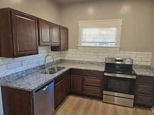 Kitchen with stainless steel appliances, dark brown cabinets, sink, and light wood-type flooring