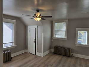 Additional living space featuring radiator, plenty of natural light, and light wood-type flooring