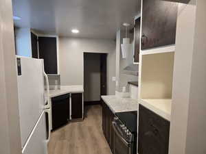 Kitchen featuring dishwasher, stainless steel range with electric stovetop, light hardwood / wood-style floors, decorative light fixtures, and white fridge