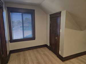 Additional living space featuring lofted ceiling and light hardwood / wood-style flooring