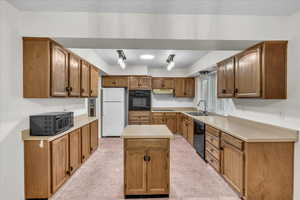 Kitchen with black appliances, sink, and a kitchen island