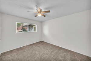 Carpeted spare room with ceiling fan and a textured ceiling