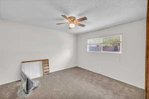 Spare room featuring ceiling fan, a textured ceiling, and carpet floors