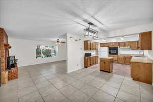 Kitchen with sink, black appliances, a center island, decorative light fixtures, and ceiling fan