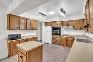 Kitchen with decorative backsplash, black appliances, sink, and a kitchen island