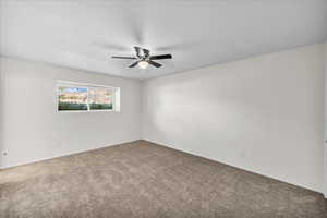 Carpeted spare room featuring ceiling fan