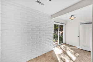 Interior space featuring beamed ceiling, brick wall, and light tile patterned floors