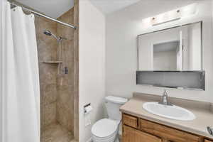 Bathroom with toilet, a shower with curtain, and vanity