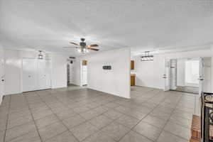 Empty room with ceiling fan, a textured ceiling, and light tile patterned floors