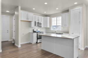 Kitchen featuring appliances with stainless steel finishes, white cabinetry, a kitchen island, and wood-type flooring