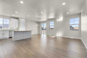 Unfurnished living room featuring light wood-type flooring, a wealth of natural light, and a notable chandelier