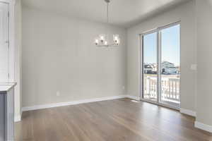 Unfurnished dining area featuring hardwood / wood-style flooring and a notable chandelier
