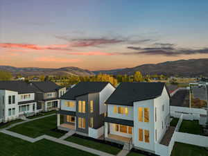 Back house at dusk with a mountain view and a lawn