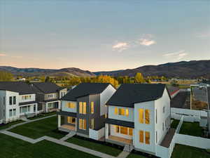 Back house at dusk with a mountain view and a lawn