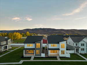 Back house at dusk featuring a yard and a mountain view