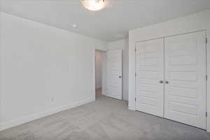 Unfurnished bedroom featuring a closet and light carpet