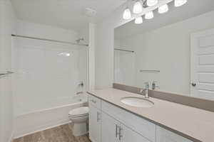 Full bathroom with vanity, toilet, wood-type flooring, and shower / washtub combination