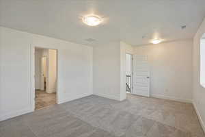 Spare room featuring a textured ceiling and light colored carpet