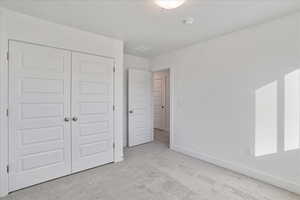 Unfurnished bedroom with a closet and light colored carpet